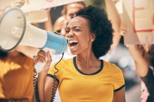 Protest, megaphone and speech of angry black woman at rally. Loudspeaker, revolution and speaking,