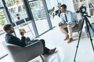 Business interview. Two young men in smart casual wear talking while making new video indoors