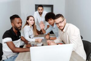 a group of people sitting on the chair while communicating on laptop