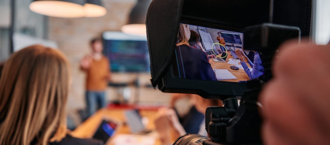 A videographer captures the essence of a business meeting in a modern office, skillfully documenting corporate dynamics and collaboration.