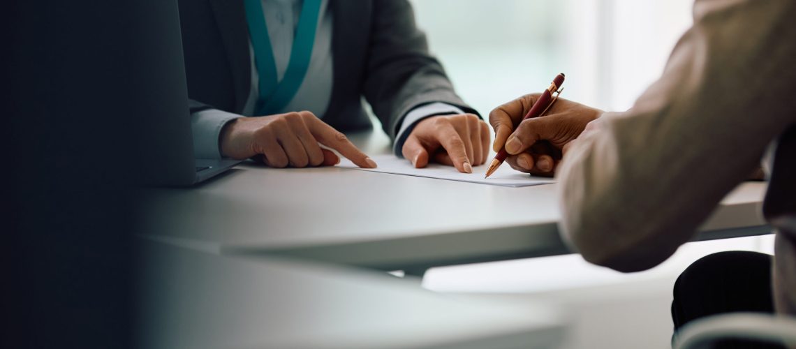 Close up of African American man signing an agreement with bank manager in the office.