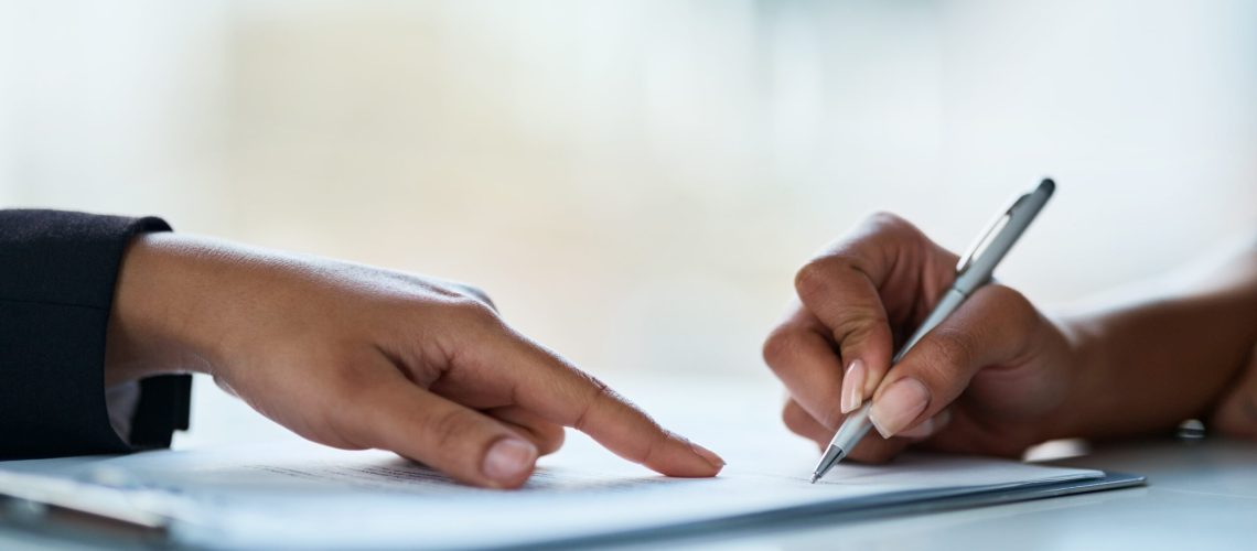 Closeup shot of two businesspeople filling in paperwork in an office.